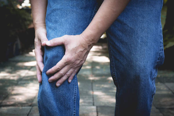 Man grabbing knee in pain, psoriatic arthritis flare up.