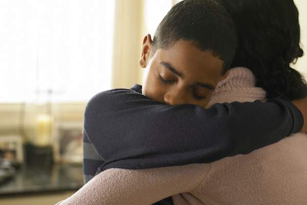 Mother hugging son.