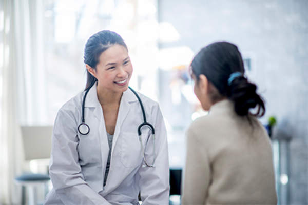 Doctor smiling at female patient wearing a sweater.