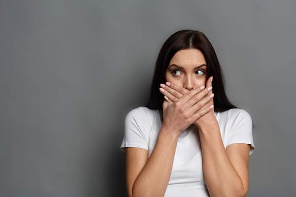 Covering mouth with hands, hiding sores.