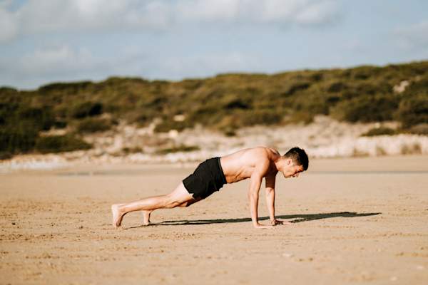 man doing yoga or pilates on the beach