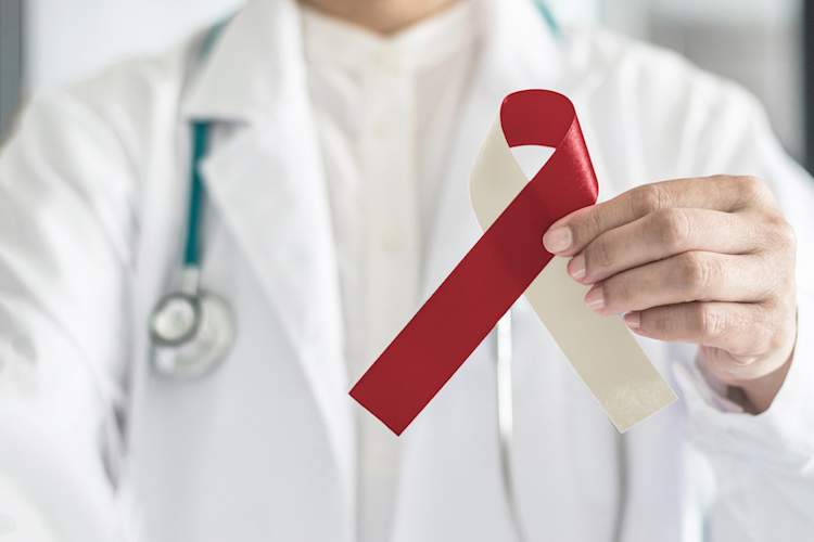 Burgundy ivory ribbon awareness on doctors hand, symbolic bow color for head and neck cancer, oral squamous cell carcinoma, throat, laryngeal and pharyngeal cancer