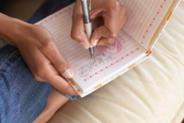 Woman sitting writing positively in her journal.
