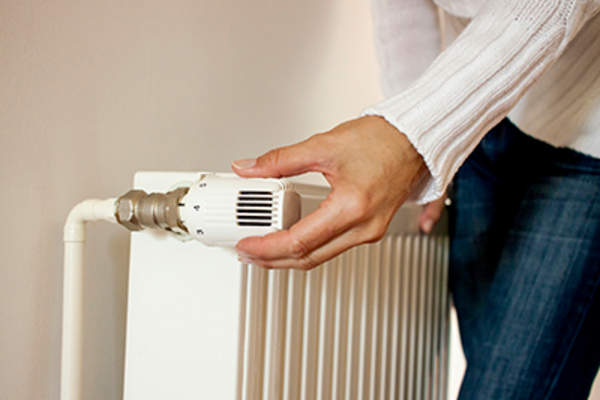 Woman adjusting a thermostat.