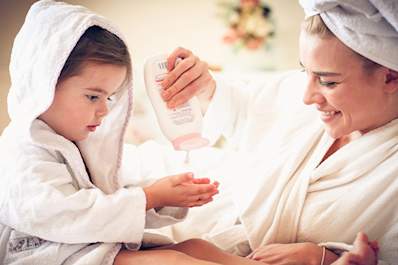 Mother putting lotion on her daughter.
