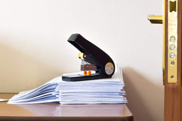 Oversized stapler on stack of papers.