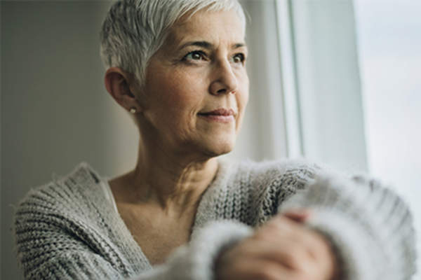 Senior woman sitting and thinking looking out the window.