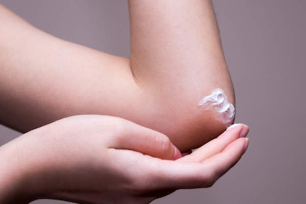 Applying moisturizer to elbow.