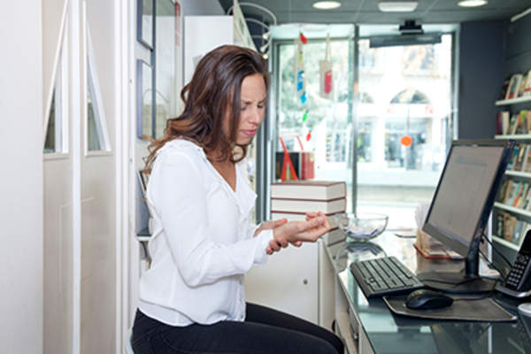 Woman experiencing hand pain at work on computer.
