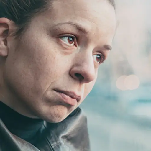 Depressed woman looking out a window.