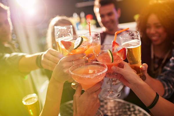 Group of friends holding up different kinds of cocktails.