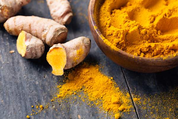 Spice: turmeric roots and powder on wood