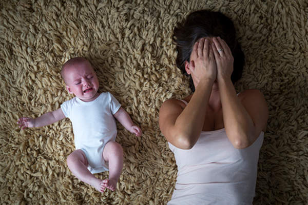 Baby crying and mother stressed image.