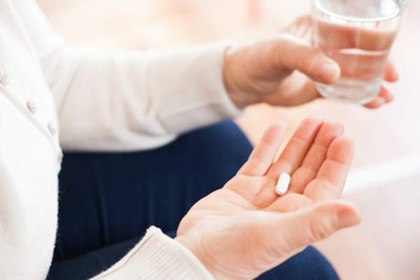 Woman taking medication with glass of water.