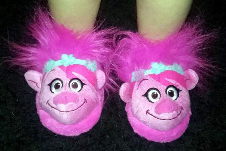 Little girl wearing troll slippers.