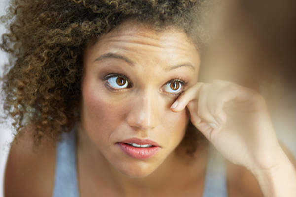 Woman looking at eye in mirror.