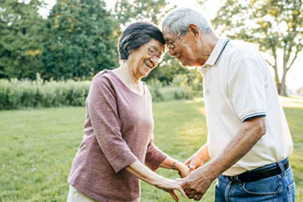 Senior couple holding hands outside in yard.
