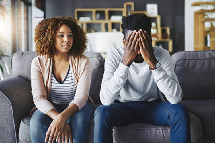 Man discussing depression with his partner on couch at home.