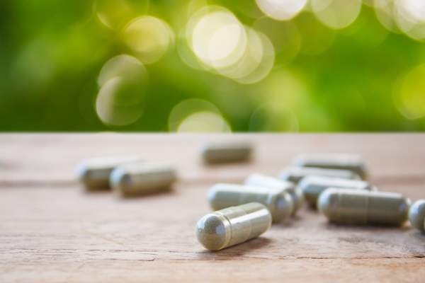 Herbal capsules on wooden table