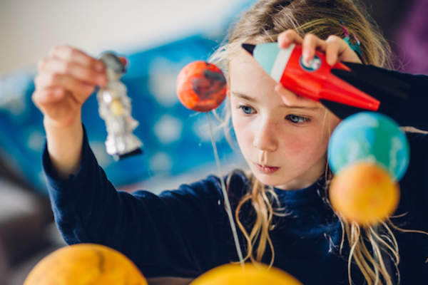 Young student learning about space while playing astronaut.