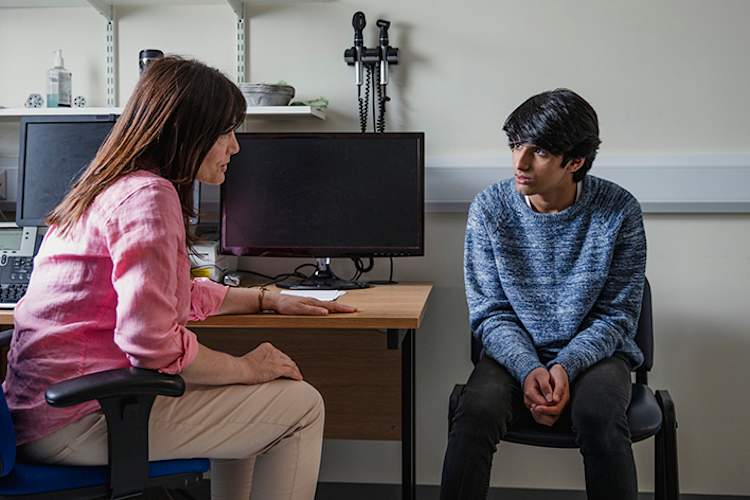 Stressed teenage boy talking to his doctor.