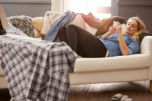 Woman lazily looking at her phone on the couch.