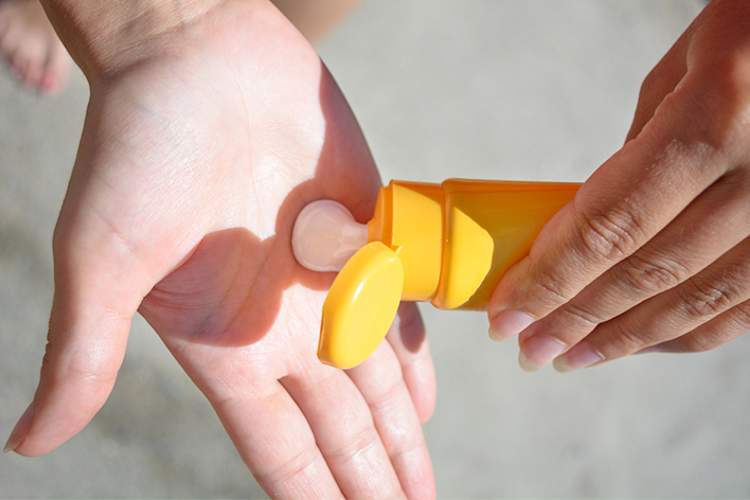 Woman appying sunscreen.