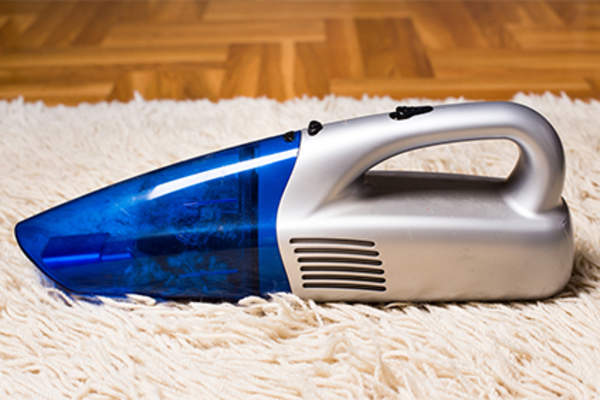 Handheld vacuum dustbuster on rug.