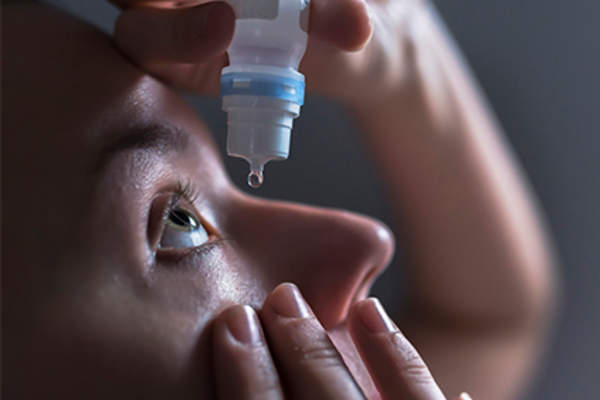 Close up of woman putting in eye drops.