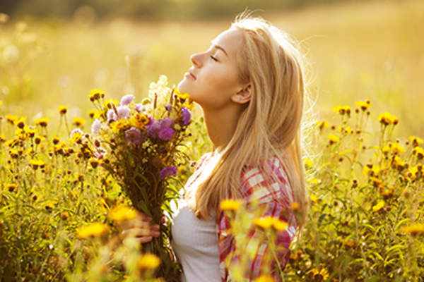 Woman smelling a field of flowers.