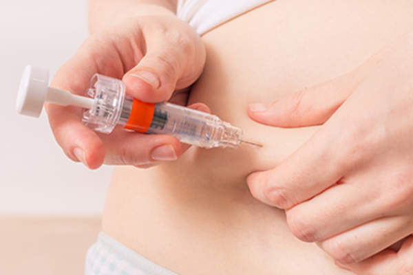Woman injecting medication into stomach skin.