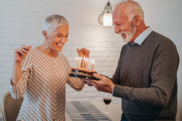 Happy senior couple celebrating special occasion with cake and candles.