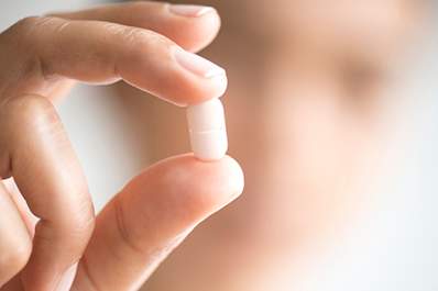 Woman holding a pill.