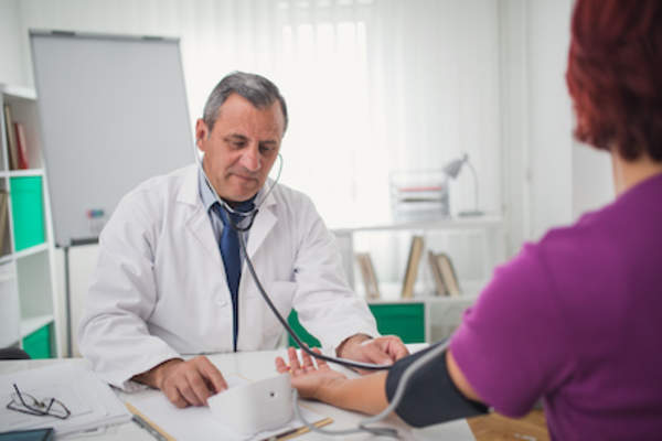 Doctor checking female patients blood pressure.