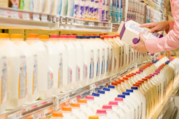Woman checking ingredients on the back of a milk carton.
