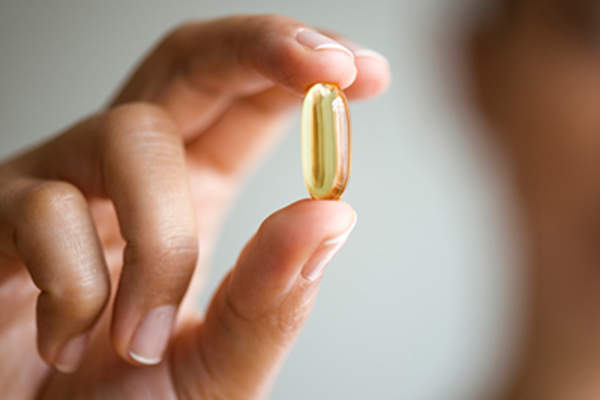 Woman holding fish oil capsule.