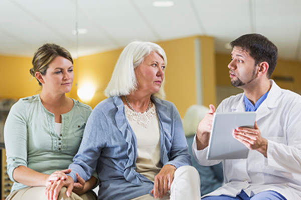 Woman with adult daughter talking to doctor