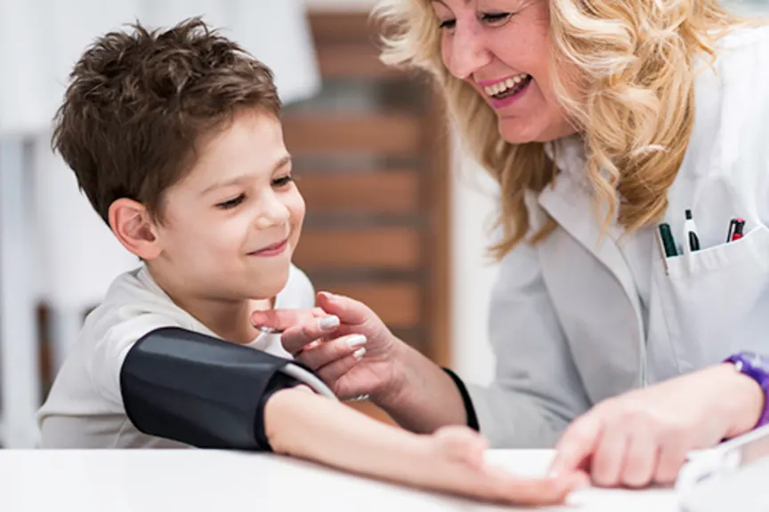 Smiling young boy getting blood pressure taken by female doctor.
