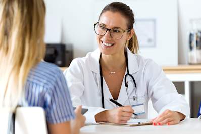 Smiling doctor talking to young woman patient.