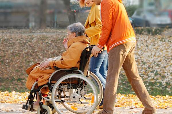 Couple pushing woman in wheelchair.