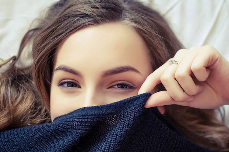 Young woman hiding face with sweater