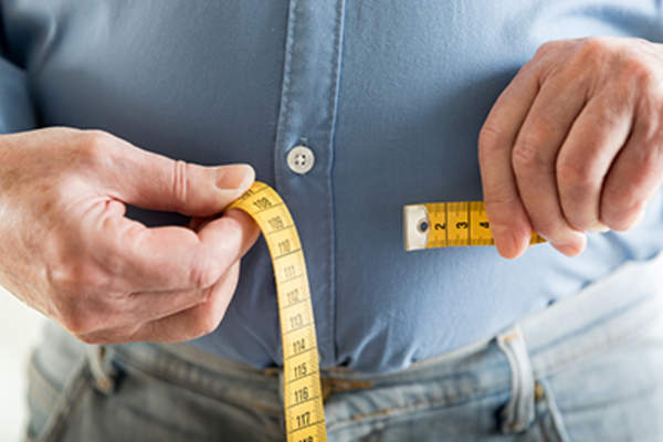 Overweight man measuring his waist.