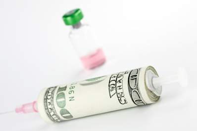 Money wrapped around syringe with vial in background.