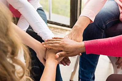 Diverse group of breast cancer survivors with hands in.