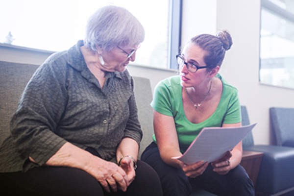 Senior woman meeting with health care representative filling out paperwork.
