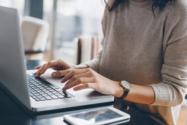 Woman typing on a laptop.