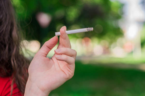 Woman smoking cigarette outside, avoid smoking and secondhand smoke if you have TED.