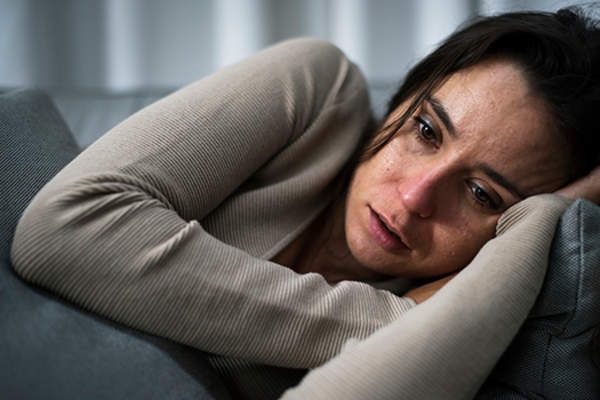 Worried woman lying on couch.