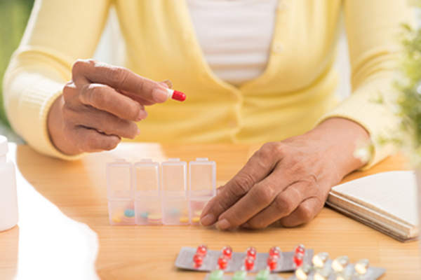 Woman organizing her medications in a pill box