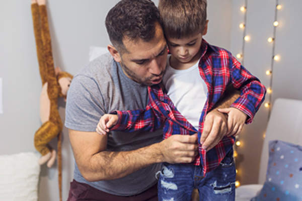 Dad helping his son get dressed.
